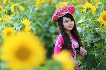 woman stands between bed of sunflower thumbnail