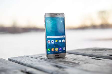 silver Samsung Galaxy Android smartphone on top of gray wooden table thumbnail