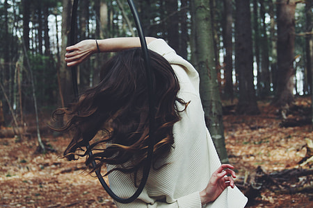 woman in gray sweater holding hula hoop in forest thumbnail