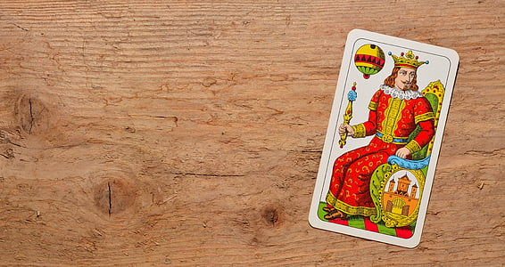 flat-lay photo of red and yellow dressed king card on brown desk thumbnail