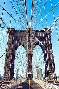 person walking on brown concrete suspension bridge at daytime thumbnail