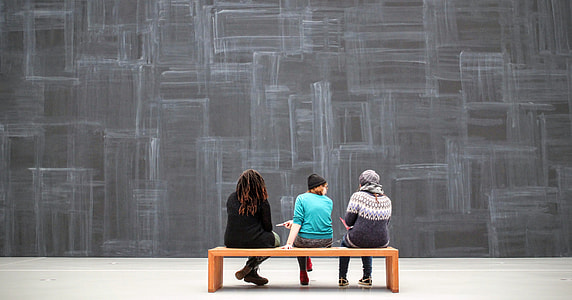 photo of three girls sitting on wooden bench chair thumbnail
