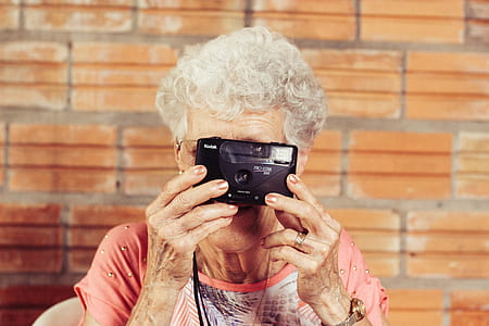 woman wearing pink and white scoop-neck shirt holding black Kodak point-and-shoot camera thumbnail