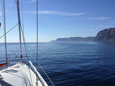 white and grey sail boat on body of water overlooking grey island at daytime thumbnail