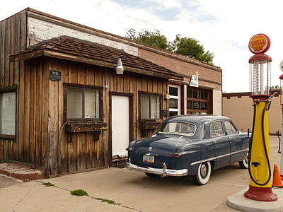 blue sedan parked beside brown wooden house at daytime thumbnail