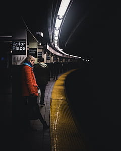 woman learning on post in front of train rail thumbnail