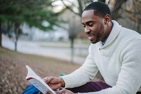 man wears white sweater and reading a book thumbnail