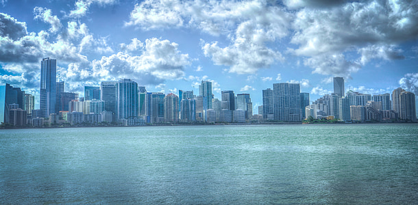 blue body of water near high rise buildings under clouds at daytime thumbnail