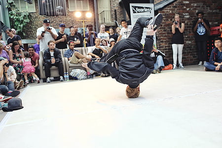 man wearing black jacket and pants doing head stand thumbnail