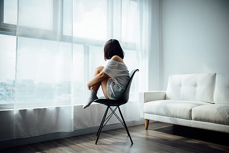 woman sitting on black chair in front of window thumbnail