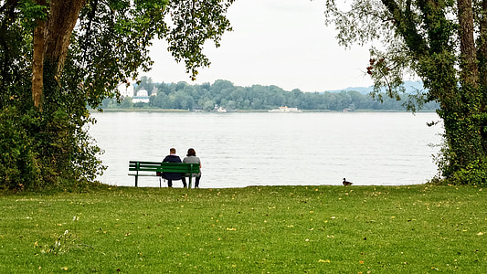 man and woman sitting on bench near body of water thumbnail