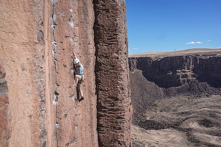 person climbing on brown rock during daytime thumbnail