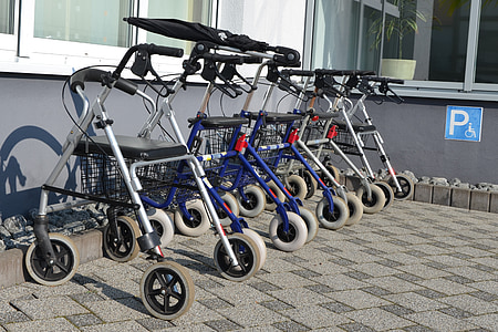 closeup photo of lined white-and-blue rollators beside gray painted wall thumbnail