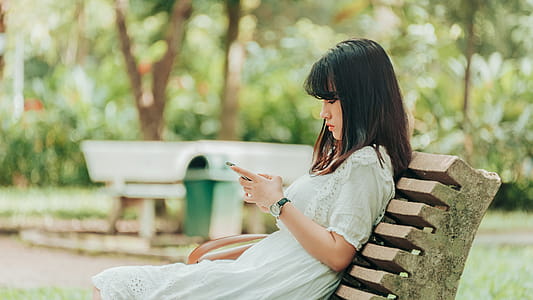 Woman Sitting on Bench Using Smartphone thumbnail