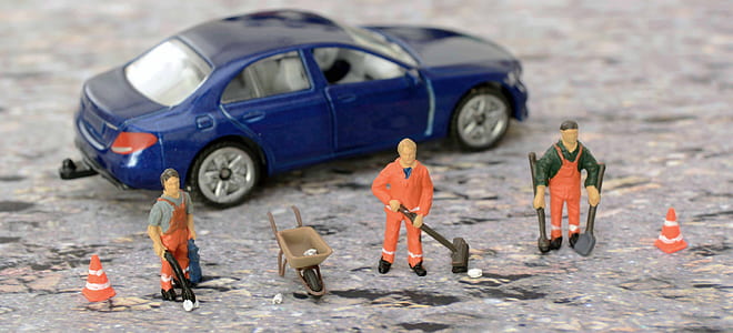 closeup photography of blue sedan and three construction men workers figurines thumbnail