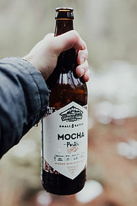 selective focus photography of person holding Mocha Porter glass bottle thumbnail