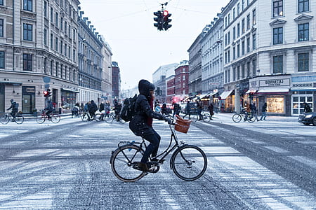 person riding bicycle on road intersection with traffic lights during daytime thumbnail