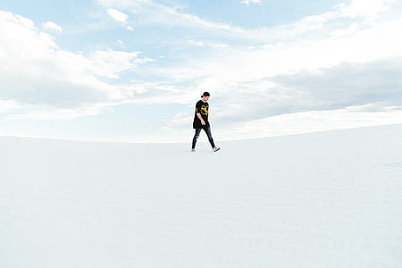 man walking along snow under alto cumulus clouds thumbnail
