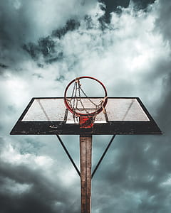 red and black basketball hoop under white clouds thumbnail