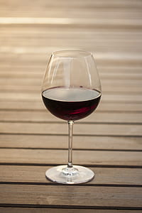 selective focus photography of wine glass filled with red beverage on brown wooden surface thumbnail