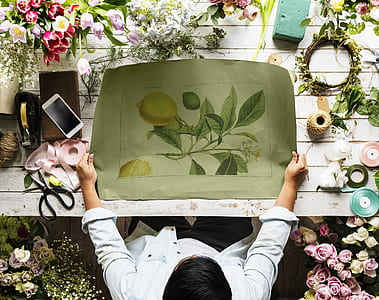 person holding yellow lemons painting on white wooden table with assorted flowers thumbnail