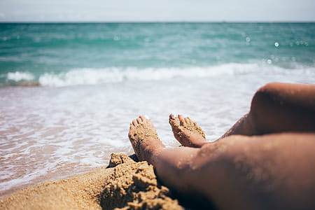 Sandy feet on the beach with waves and horizon in the background thumbnail