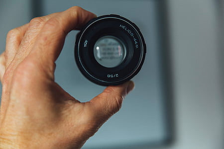 person holding black camera lens thumbnail