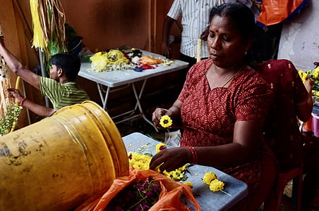 woman sitting on red stool while holding yellow flower thumbnail