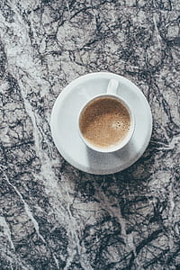 white cup with coffee and saucer on grey marble top thumbnail