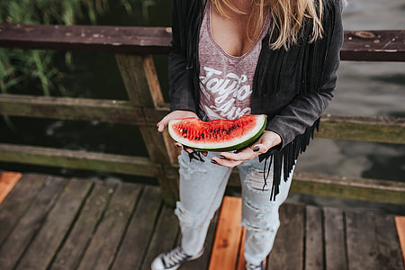Blonde woman having a healthy snack at the wooden pier thumbnail
