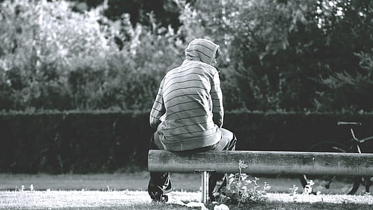 grayscale photography of man sitting on bench thumbnail