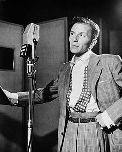 grayscale photography of man standing in front of microphone thumbnail