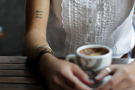 person sitting in front of table while holding cup of coffee thumbnail