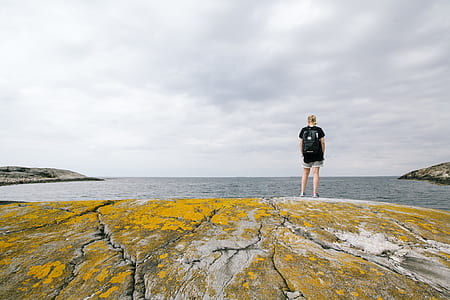 person standing on rock looking at body of water thumbnail