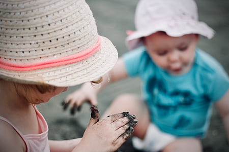 girl and toddler playing on mud during day thumbnail
