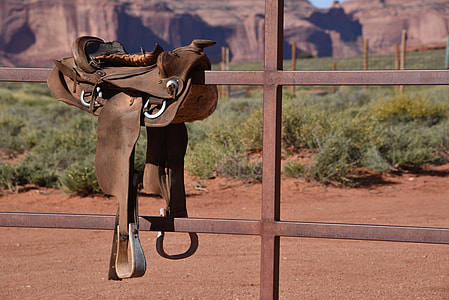 brown horse saddle on wooden fence during daytime thumbnail