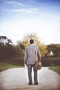 man in gray suit jacket and blue jeans walking in street during daytime thumbnail