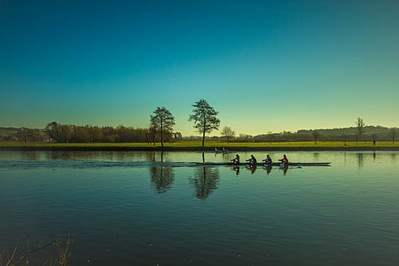 four people in boat in front of tall tees thumbnail