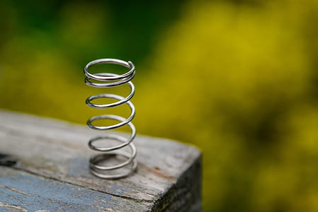 gray steel spring on brown wooden surface thumbnail