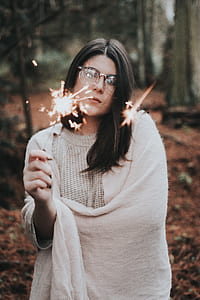 woman holding sparkler standing near tree thumbnail