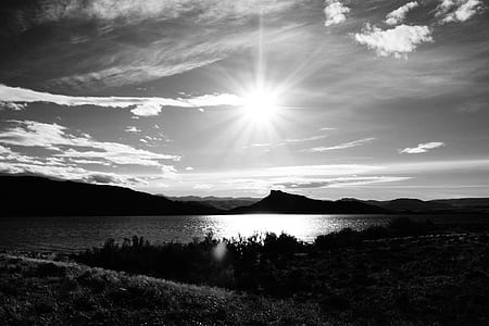 grayscale photo of body of water surrounded with mountains thumbnail
