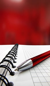 close up photography of red pen on top of spiral notebook thumbnail
