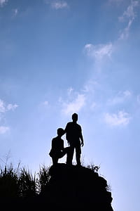silhouette photo of two boy standing on heels under blue sky thumbnail