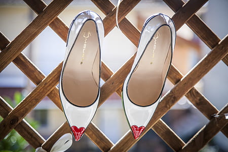 pair of women's white shoes hanging on wooden rack thumbnail