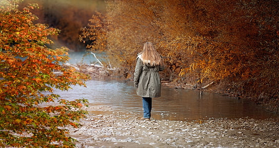 woman wearing gray jacket near body of water thumbnail
