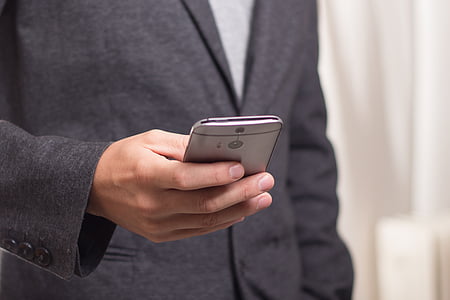 man in black suit holding HTC One M8 smartphone thumbnail