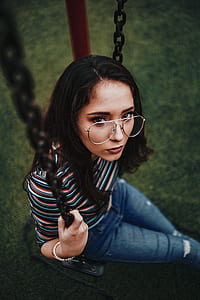 woman wearing eyeglasses sitting on outdoor swing thumbnail