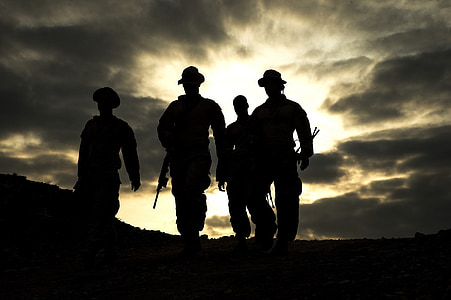 silhouette photo of four man walking on pathway carrying weapons thumbnail
