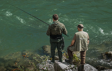 man holding fishing rod beside body of water thumbnail