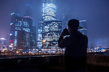 person taking photo of lighted city buildings thumbnail